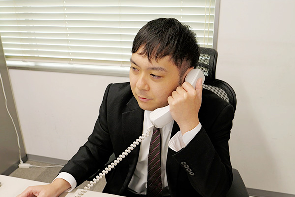 オフィス内で同僚と打ち合わせする男性スタッフ